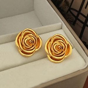 Detail of high-polished golden rose stud earrings on a grey velvet jewelry display box