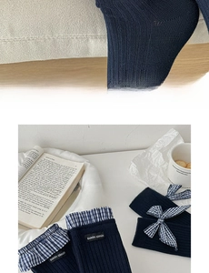 Close-up of navy blue knit socks featuring plaid lace trim and a delicate bow detail