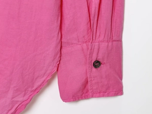 Close-up of bright pink pleated cuff with dark button on a long-sleeve cotton shirt