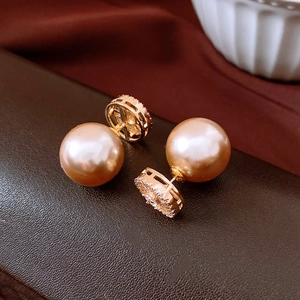 Macro view of luxury 14k gold-plated pearl earrings with shimmering zircon details