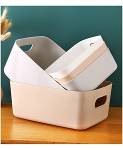 Close-up of stacked plastic storage boxes with handles on a wooden table desk