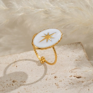 Détail de bague étoile dorée réglable avec ovale en émail blanc sur une pierre