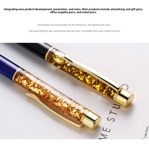 Detail of blue and black metal ballpoint pens with liquid gold glitter in transparent tube
