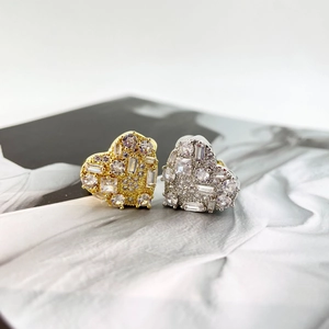 Close-up of gold and silver heart rings with pave-set cubic zirconia on a magazine