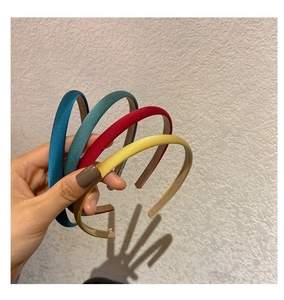 Détail de quatre serre-têtes en satin colorés bleu, vert, rouge et jaune