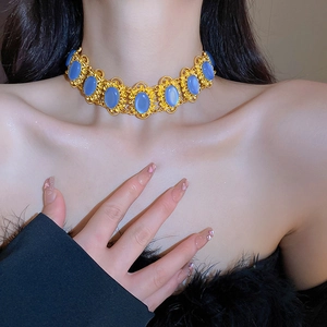 Close-up of vintage choker necklace with golden filigree and blue oval gemstones