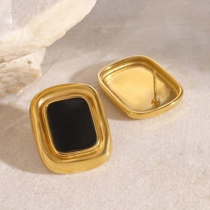 Elegant gold-framed rectangular stud earrings with black resin inlay on stone surface