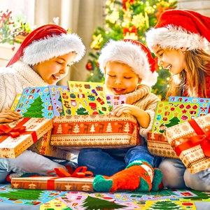 Three happy children in Santa hats opening Christmas tree sticker gift boxes by a tree