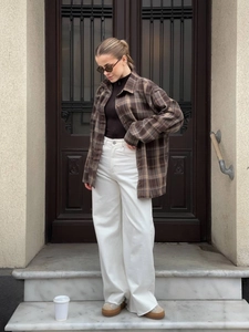 Street style view of a brown plaid oversized shirt jacket with high-waisted white trousers