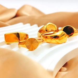 Set of assorted gold stainless steel rings with heart and geometric patterns on white fabric