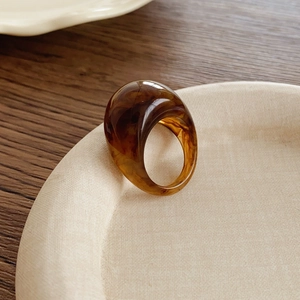 Vue détaillée d'une bague ovale en résine écaillée aux motifs ambrés sur plateau