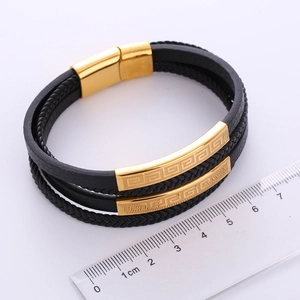Macro detail of men's multi-layer braided leather bracelet with gold magnetic clasp