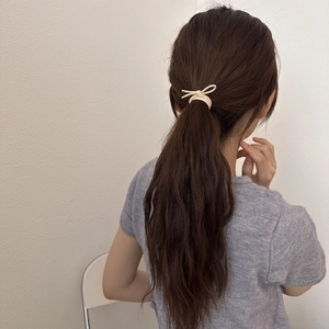Élastique à nœud beige minimaliste porté par un modèle pour une coiffure élégante