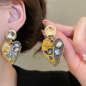 Detail of vintage heart earrings with pearl inlay and shell fragments in gold frame