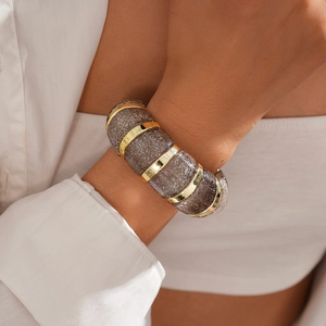 Detail of wide acrylic bracelet with gray resin links, gold rings, and silver glitter