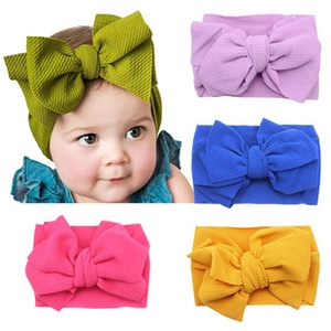 Detailed view of colorful ribbed fabric baby headbands with large bows in five vibrant colors