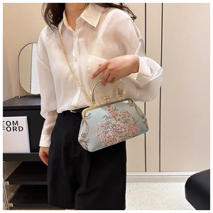 Detail of light blue vintage handbag featuring floral embroidery and gold chain strap