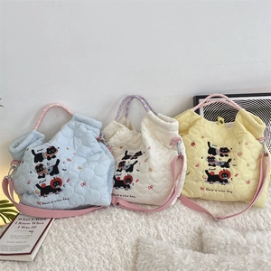 Détail de la texture matelassée en cœur sur des sacs en coton brodés de chats