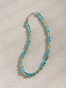 Close-up of glacier blue cat eye beads and gold metal links on a beaded necklace chain