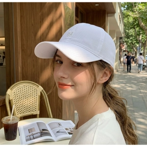Close-up of white breathable mesh baseball cap with shield logo in outdoor cafe setting