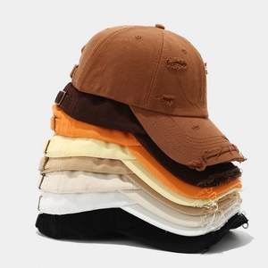 Detailed stack of distressed cotton baseball caps showing ripped brims and various colors