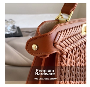 Close-up of brown woven leather texture and premium gold metal hardware on the handbag