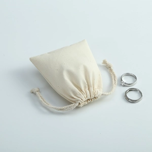Detailed close-up of a cream cotton-linen drawstring bag with silver jewelry props