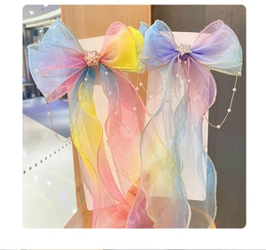 Close-up of rainbow gradient tulle bow clips with pearl flower and dangling star tassels