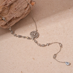 Detail of silver rose pendant with sparkling crystals and a blue teardrop stone