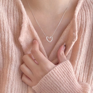 Elegant 925 sterling silver heart pendant necklace on a pink knitted sweater background