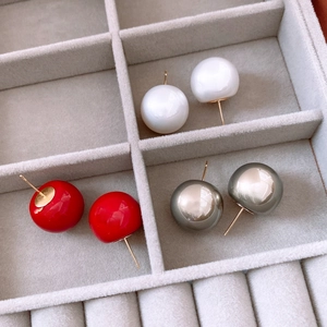 Detailed view of three pairs of round pearl earrings in white, red and metallic gray finish