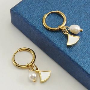 Elegant gold titanium earrings with white pearls and shell-shaped charms on a jewelry box