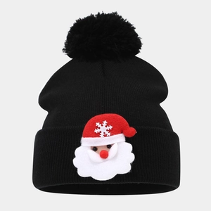 Detailed knit texture of a black winter hat featuring a plush pom-pom and Santa patch