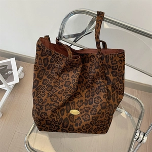 Close-up of leopard print tote bag with metallic logo plate on a stylish chair