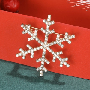 Close-up of golden snowflake brooch with sparkling white crystals on red and green background