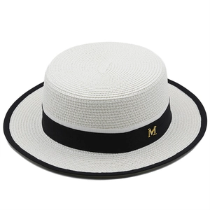 Dettaglio della trama del cappello di paglia bianco con nastro nero e decoro M in oro