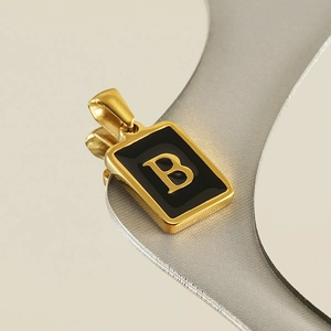 Macro shot of 18K gold letter B pendant with black enamel inlay on rectangular base