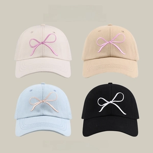 Detail of embroidered bow on sun caps in beige, khaki, light blue and black colors