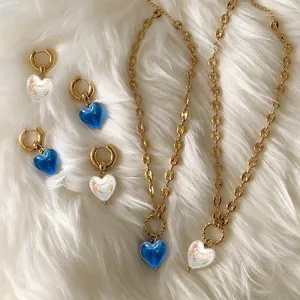 Blue and gold heart pendant necklace and earrings set on white fur background