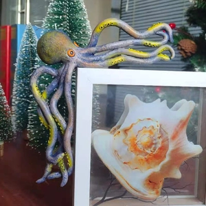 Modern resin octopus figurine with blue and yellow suckers climbing a conch frame