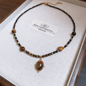 Close-up of tiger eye stone pendant and colorful beads on a jewelry display tray