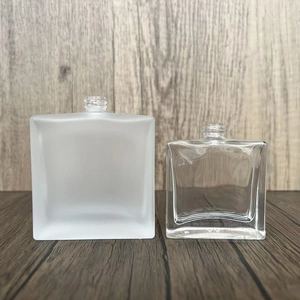 Close-up of clear and frosted square glass perfume spray bottles on a wooden surface