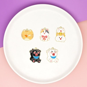 Flat lay of five cute cartoon cat charms made of colorful alloy enamel on a pink base