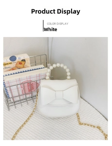 Detail view of white mini crossbody bag with large bow and pearl handle on metal rack