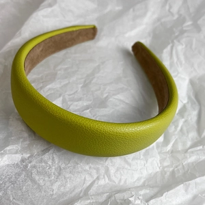 Macro detail of bright green litchi texture leather padded headband on white paper