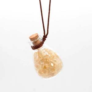 Detailed macro view of a clear glass perfume bottle pendant with yellow crystal stones