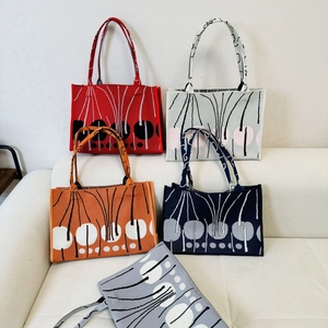 Close-up of assorted knit tote bags with abstract flower patterns in five vibrant colors