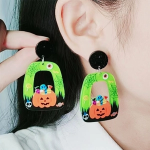 Halloween acrylic earrings with pumpkin and spider web designs on a model