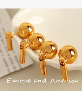 Macro shot of 18k gold plated stainless steel ball earrings on white ceramic