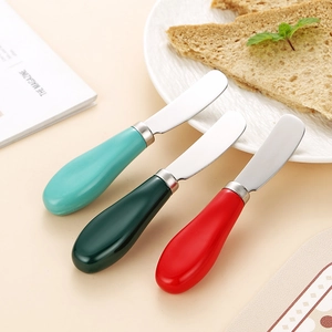 Tre coltelli da burro in acciaio inox con manici in ceramica colorati sul tavolo